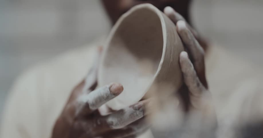 Man is holding a clay bowl that he made