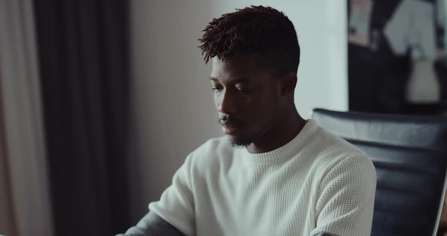 Young man sits on a desk at home and starts working on a laptop