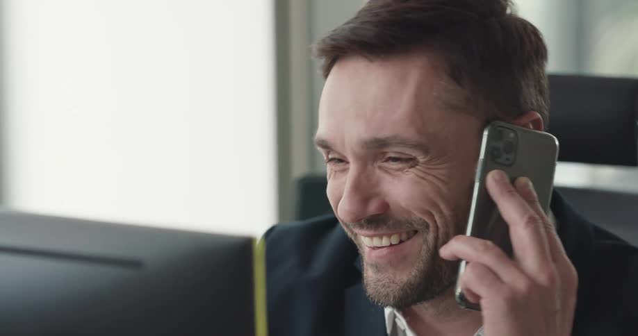 A man talks on his cell phone at his computer