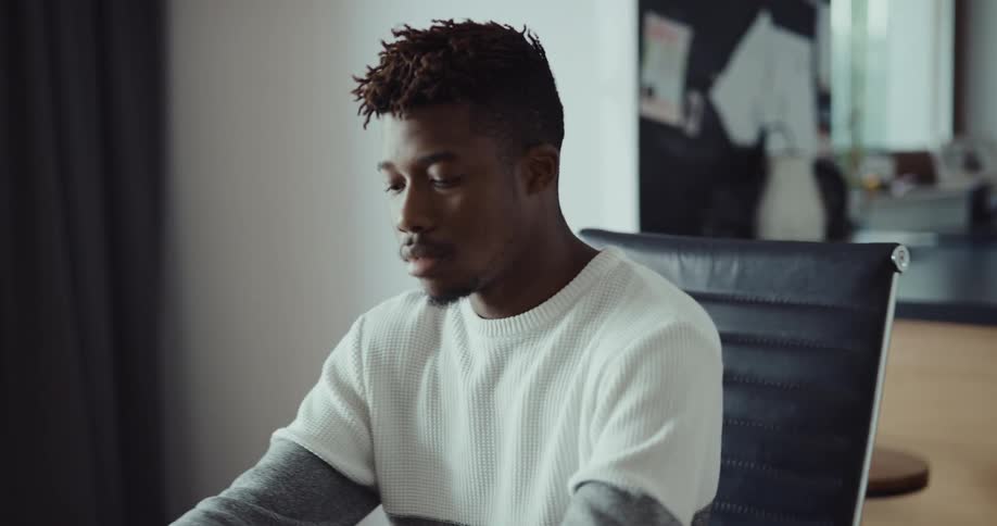 A man is typing on his laptop and sitting indoors