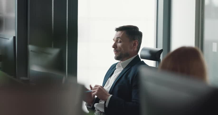Nervous office worker fiddling with a pen while thinking and waiting sitting at his desk