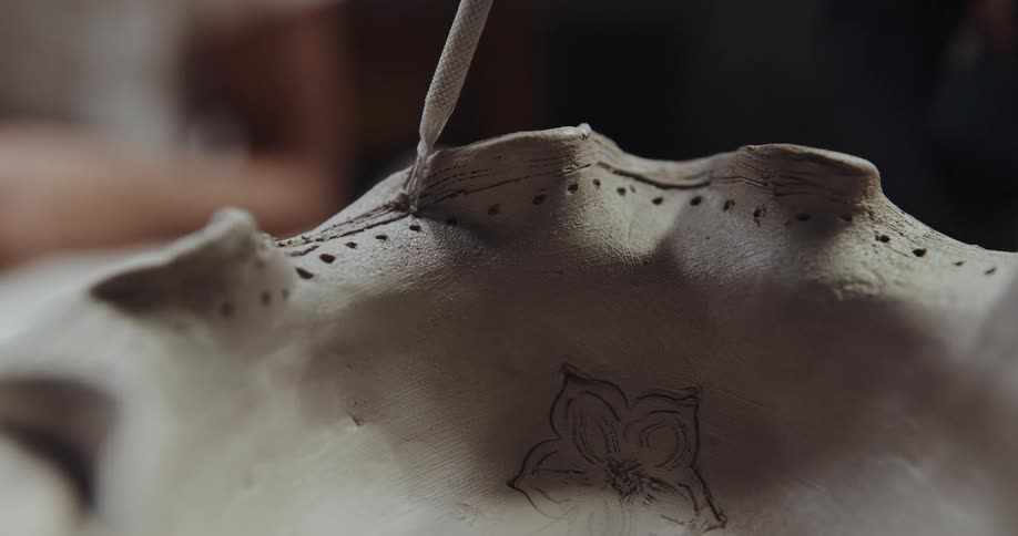 A person is etching into a clay sculpture