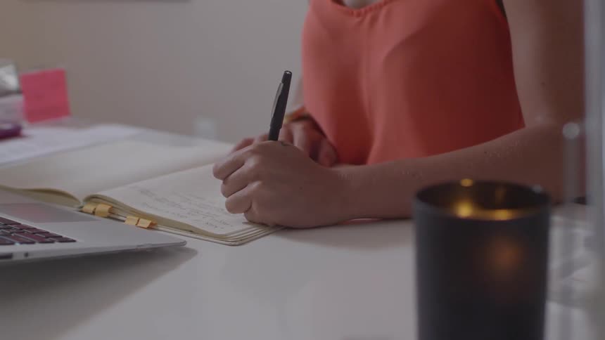 A woman is writing in a notebook