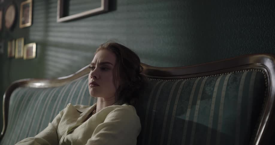 Angry teenage girl sitting on a striped couch in a living room