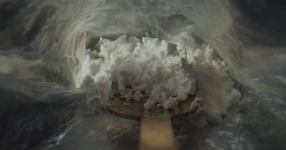 Pov shot of a spatula taking cocaine out of a plastic transparent bag