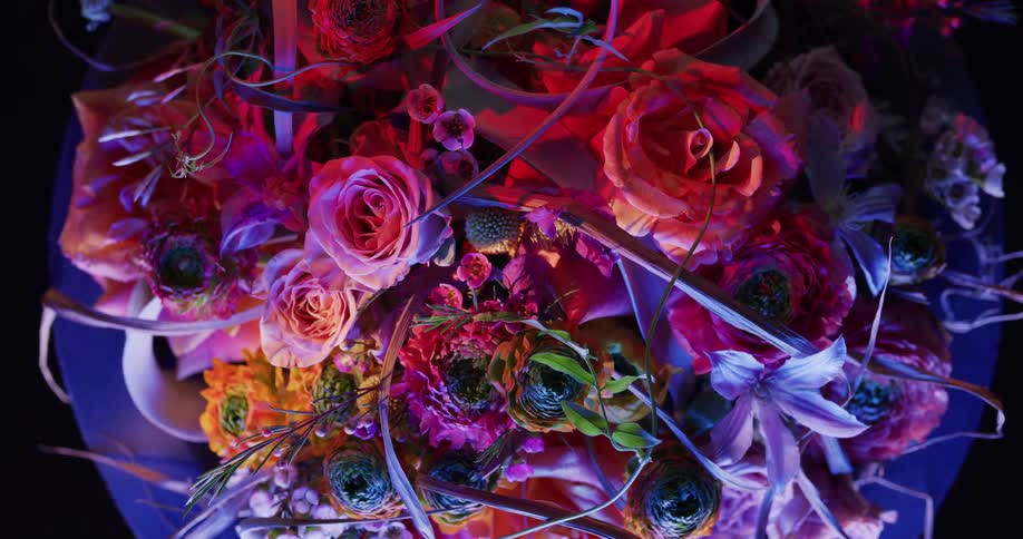 Vivid colorful floral display sits on a table in a dark room