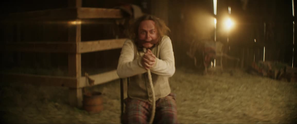 Bound and gagged man tries to scream and struggle while sitting in a chair in barn