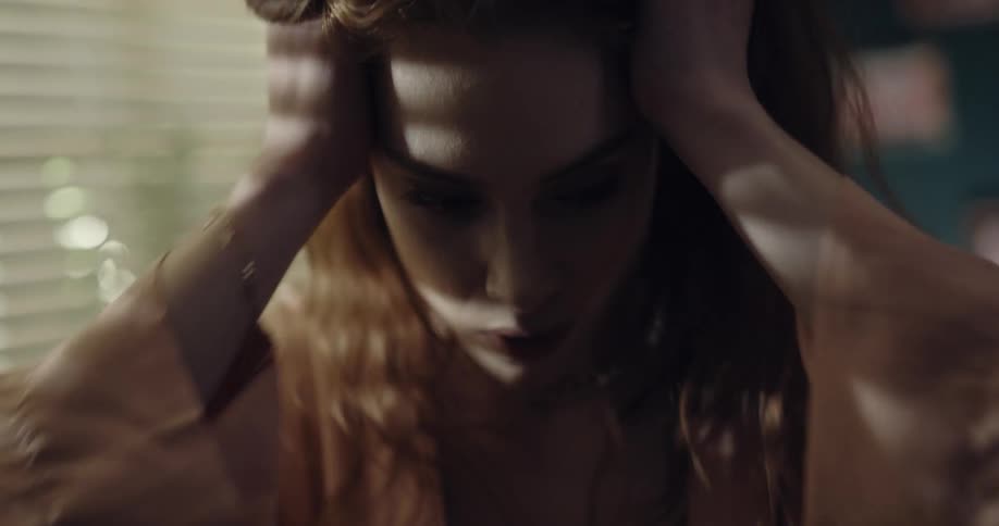 A female is standing by a window and looks upset