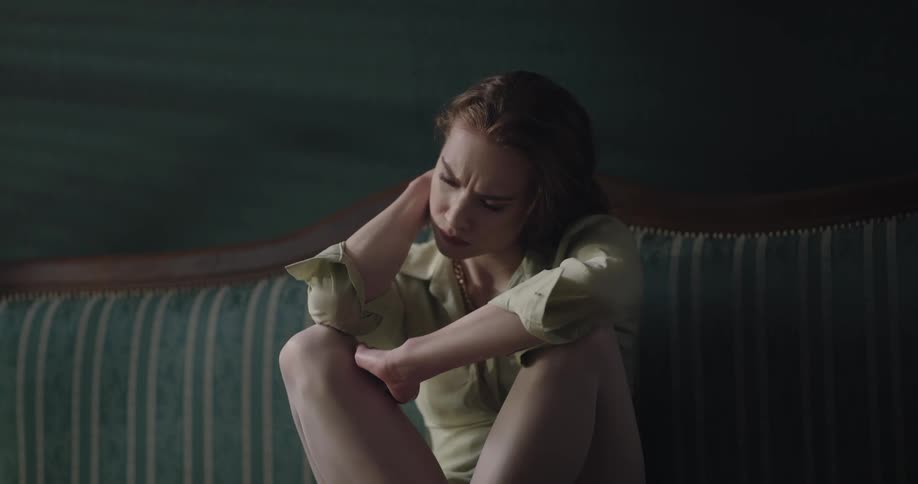 A woman sits on the couch worried