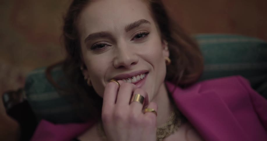A woman is resting on a couch and smiling