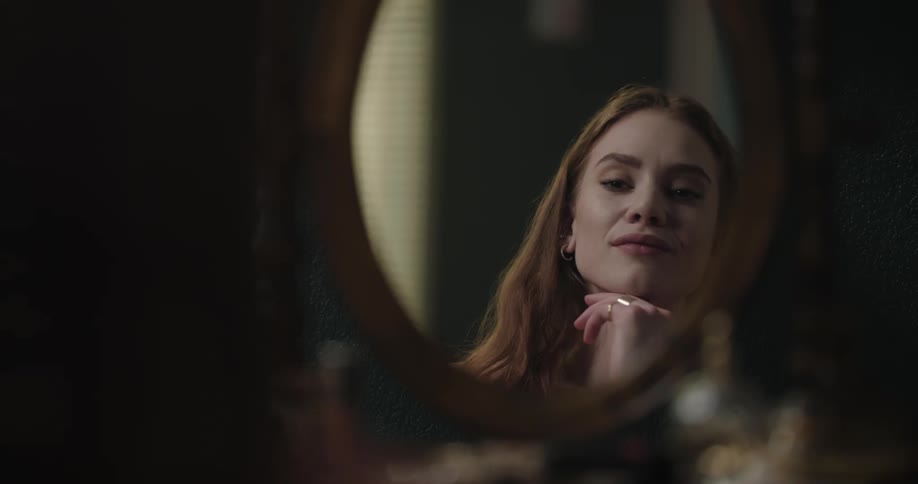 A woman is looking at her reflection in a mirror