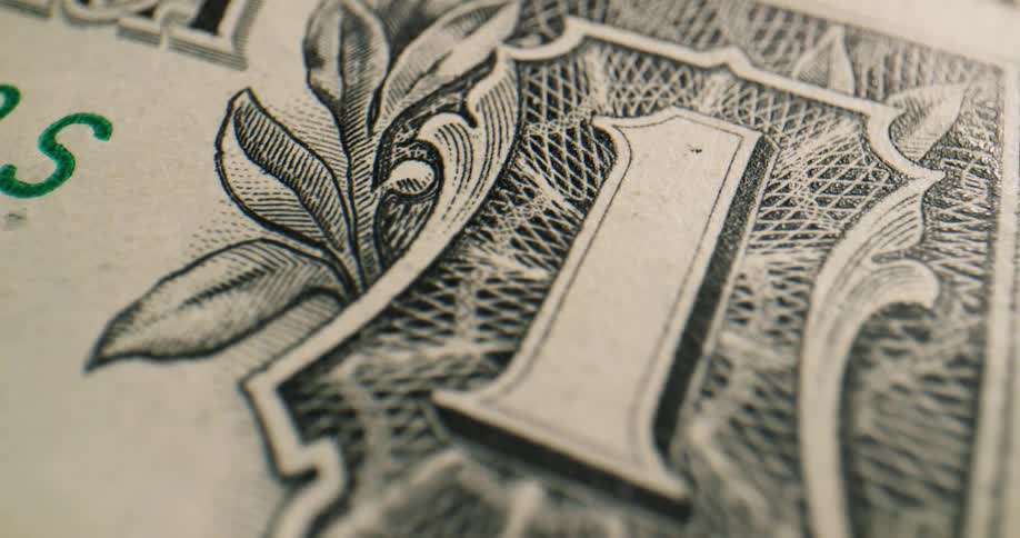 A one dollar bill sits on top of another bill