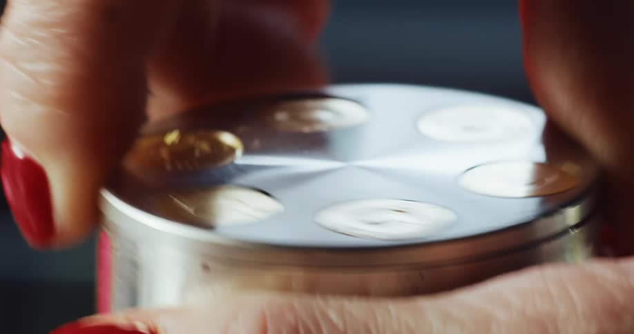 Person puts dried marijuana into metal container and turns lid to break down cluster