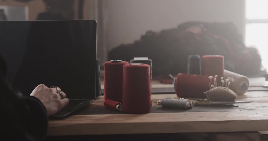 A person is sitting by their laptop at a wooden table