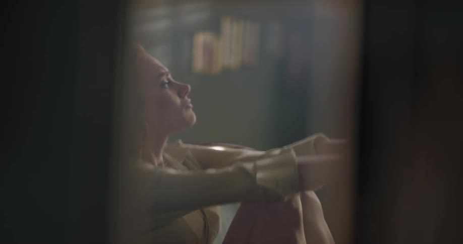 A woman is sitting indoors and looks upset