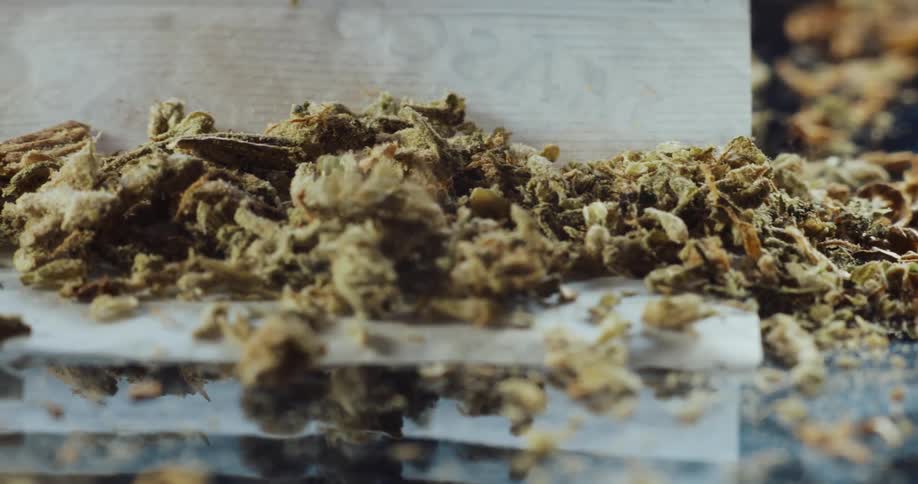 Dried flowers are dropped onto a paper on a table