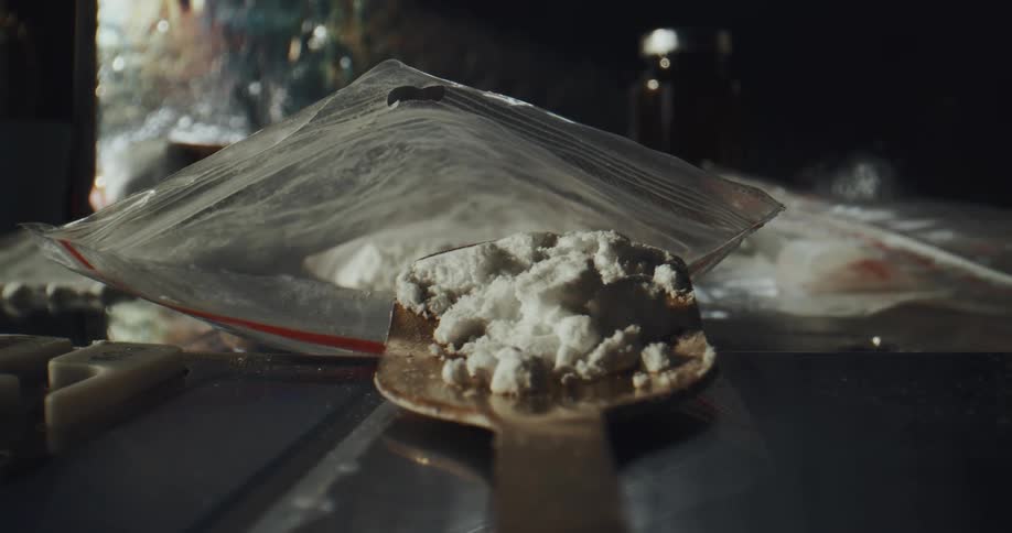 White powdered substance is removed from plastic bag with a spoon