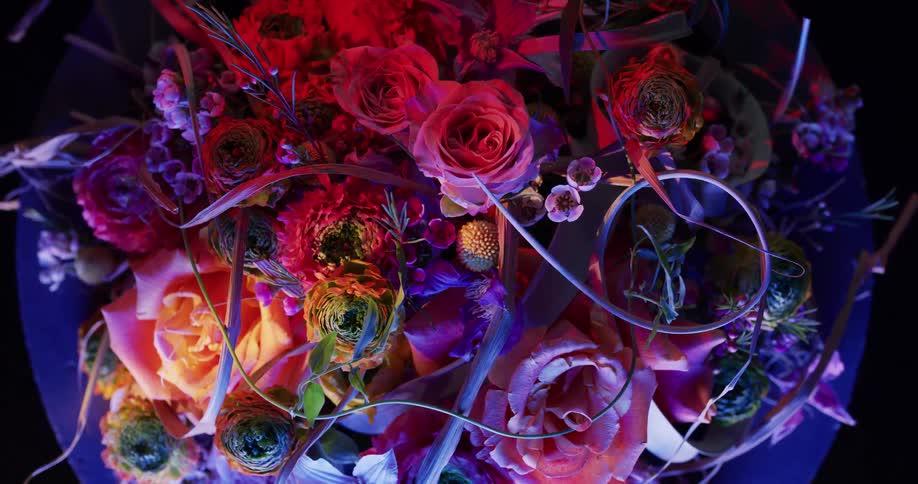 Top down twisting footage of flowers in a bouquet under colorful lights
