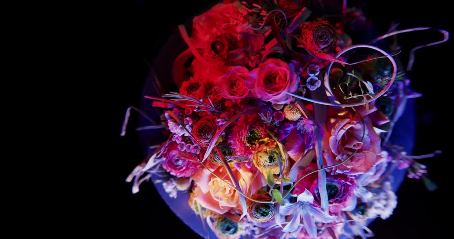 A purple hued light shines down on a floral bouquet