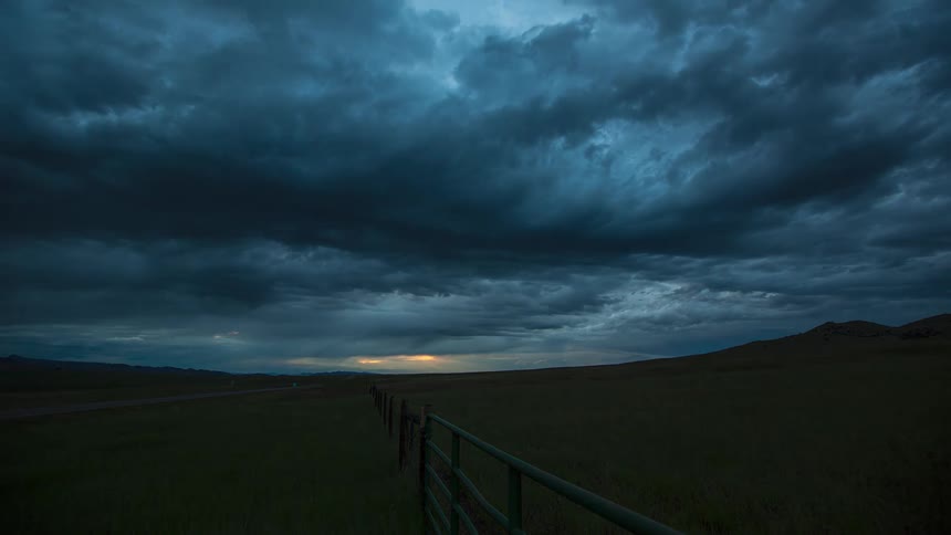 Clouds move over rural land as the sky gets darker and automobiles travel on the road