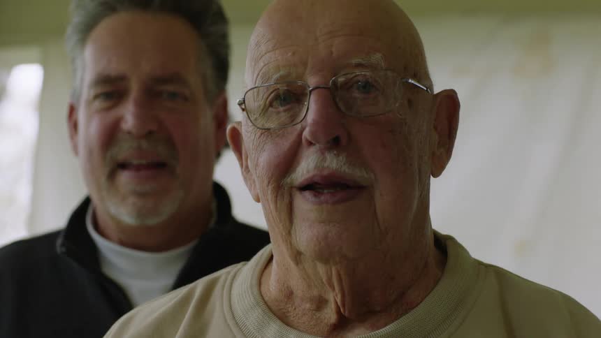 Two men stand together smiling