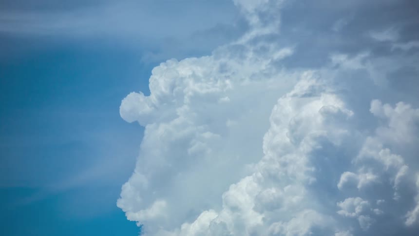 Cumulus clouds grow as they move across a blue sky