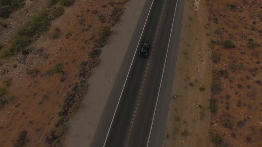 A car drives down a desert road