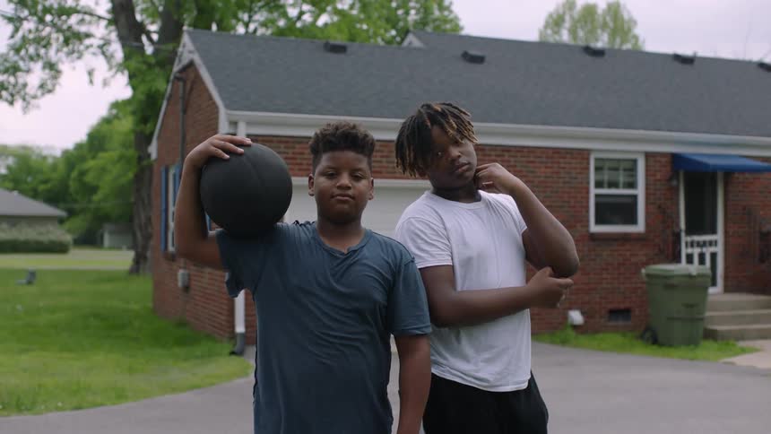 Two youths pose with basketball near home