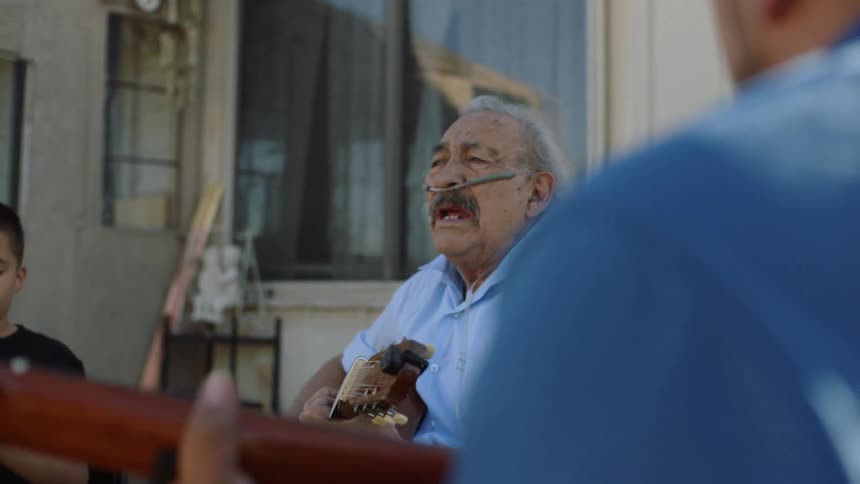 Three generations of men playing music together and singing in the neighborhood