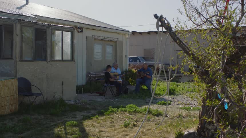 Boy sits inbackyard and listens as two guitarists play