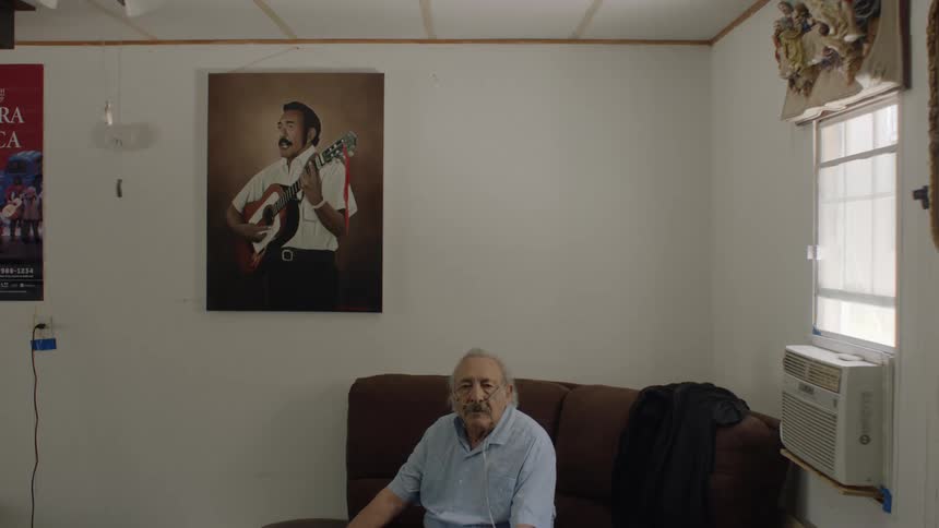 Man talking while sitting on the couch at home near a window
