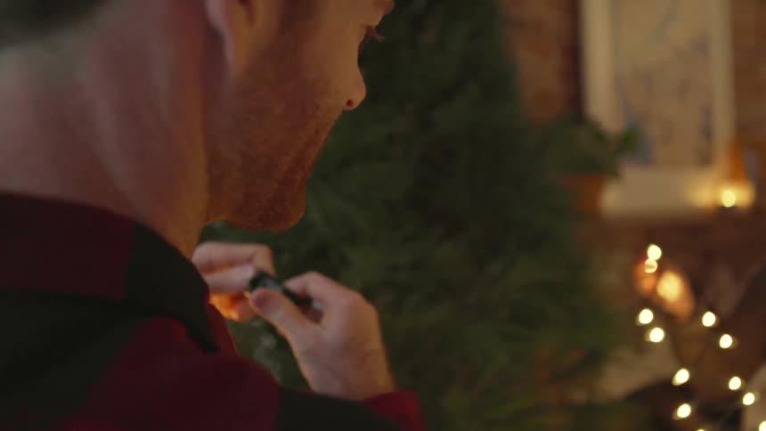 A man smiles while plugging in christmas tree lights
