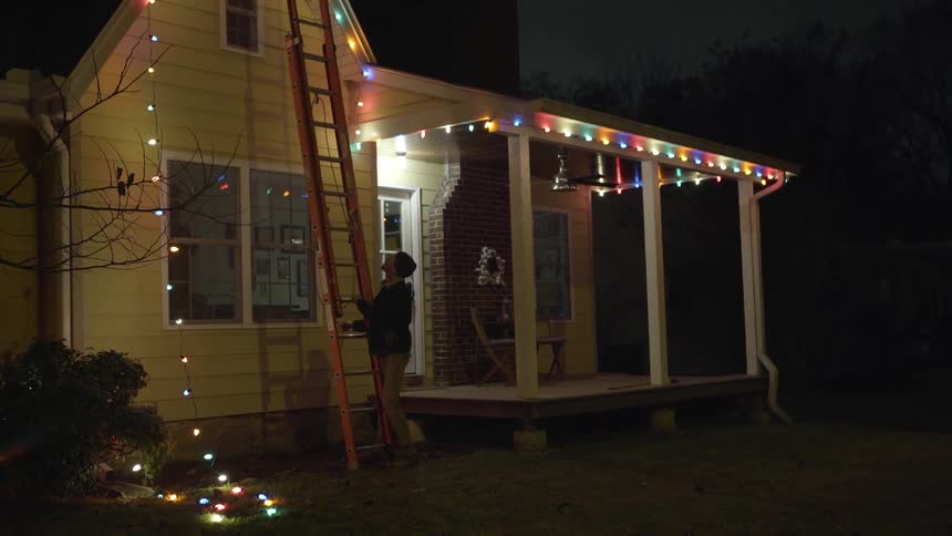 A man moves the ladder away from the house and pulls the rope to adjust