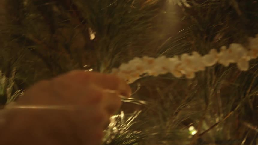 Couple decorating their christmas tree with a string of popcorn garland