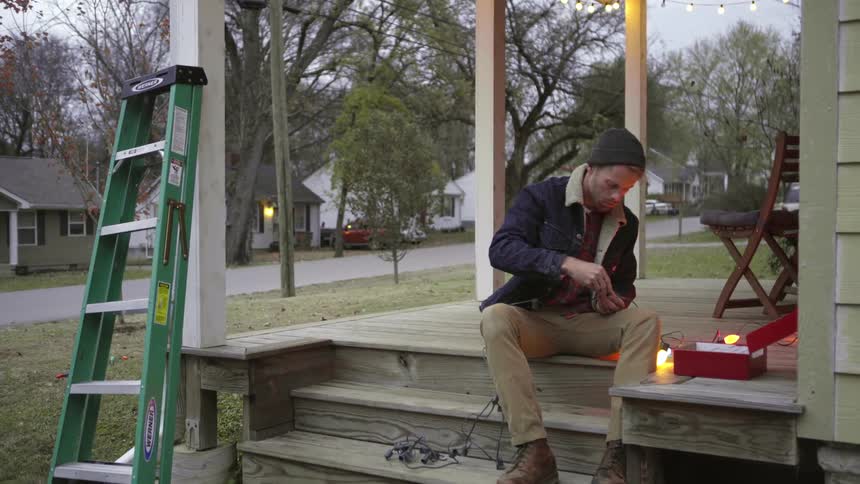 A man hangs christmas lights on a house