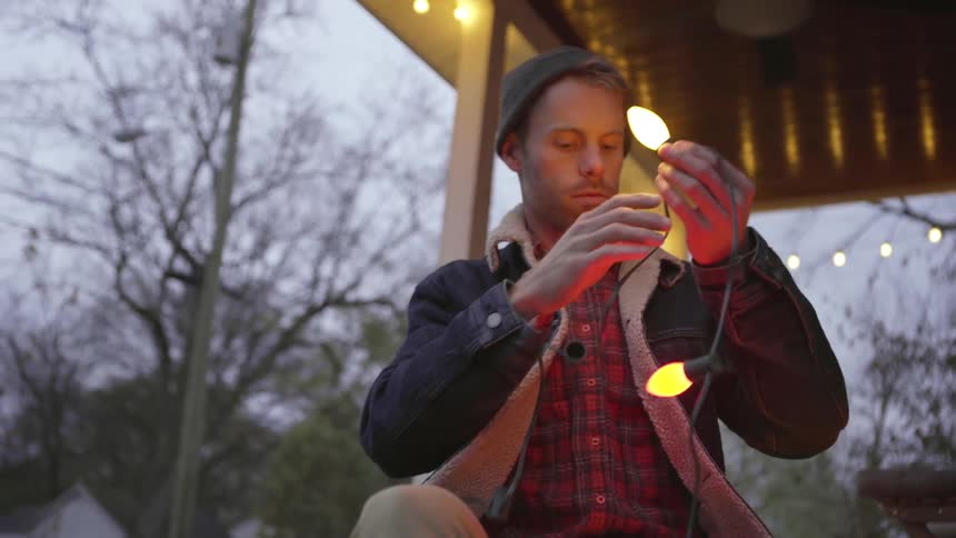A man is screwing in light bulbs onto a string of lights