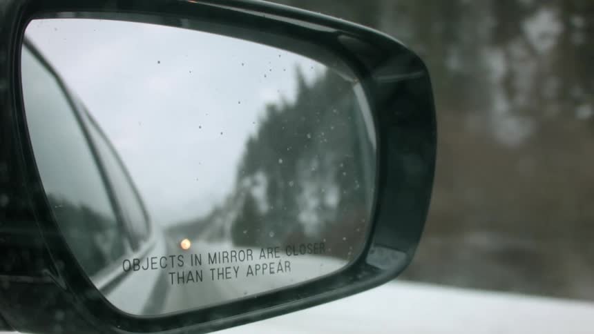 Snow covered road in a side view mirror