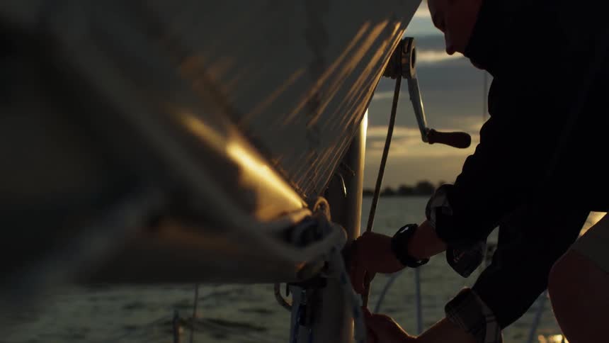 A man ties a sail on his boat