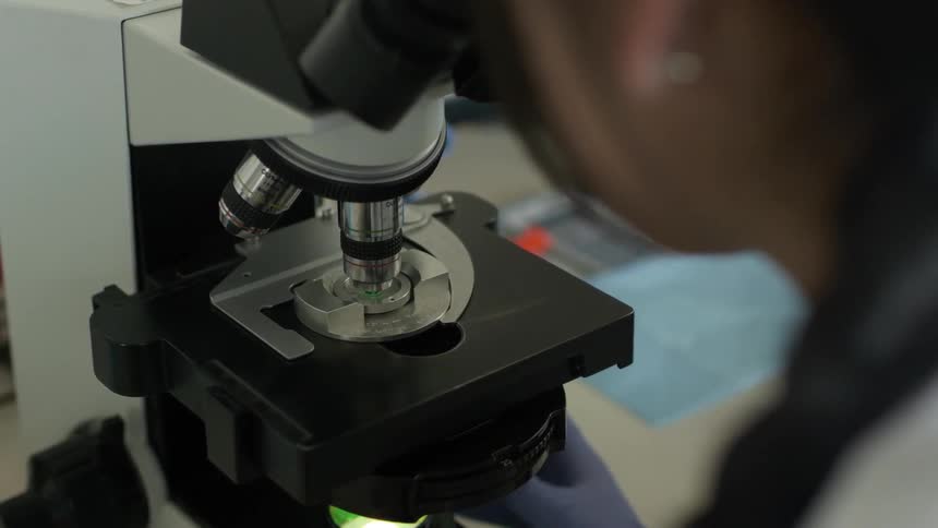A female scientist is using a microscope