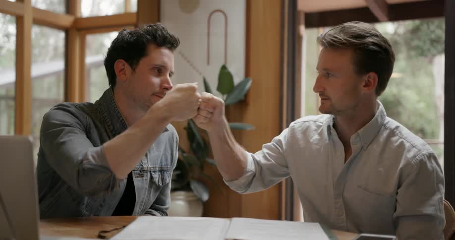 Two men bump fists and smile while in a building