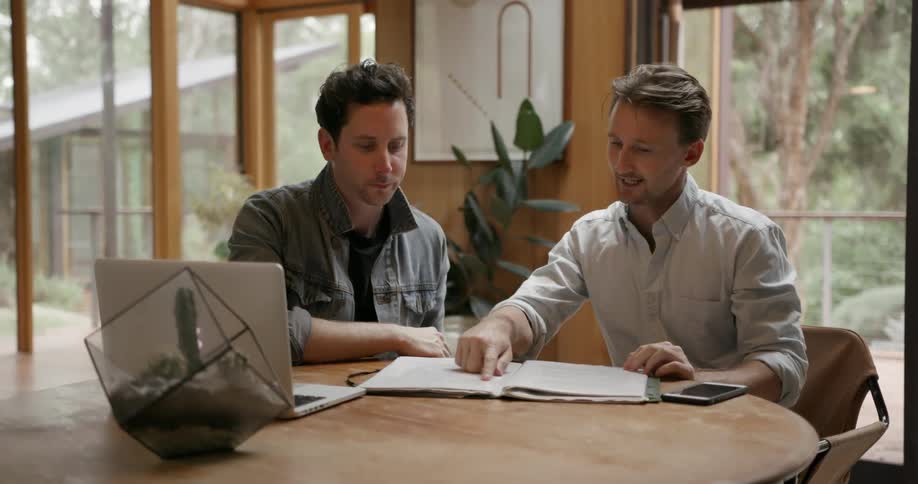 Two men go over documents while sitting at a table