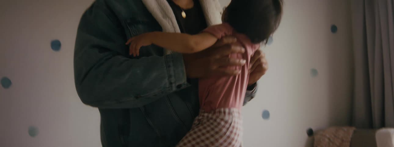 Father picking up infant daughter from changing table