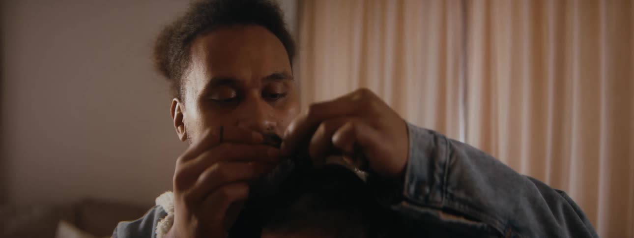 A father is putting his kids hair in a pony tail