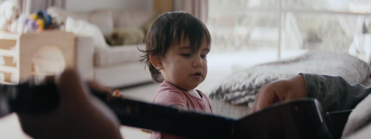 Baby taps on the guitar helping dad play