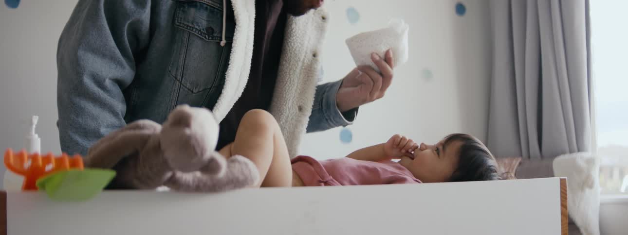 A father is holding a diaper and talking to his daughter