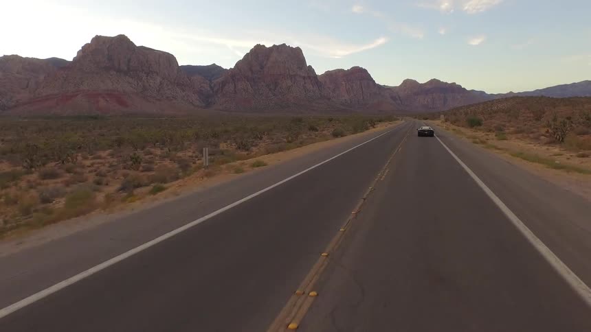 A car rides down a road towards a mountain