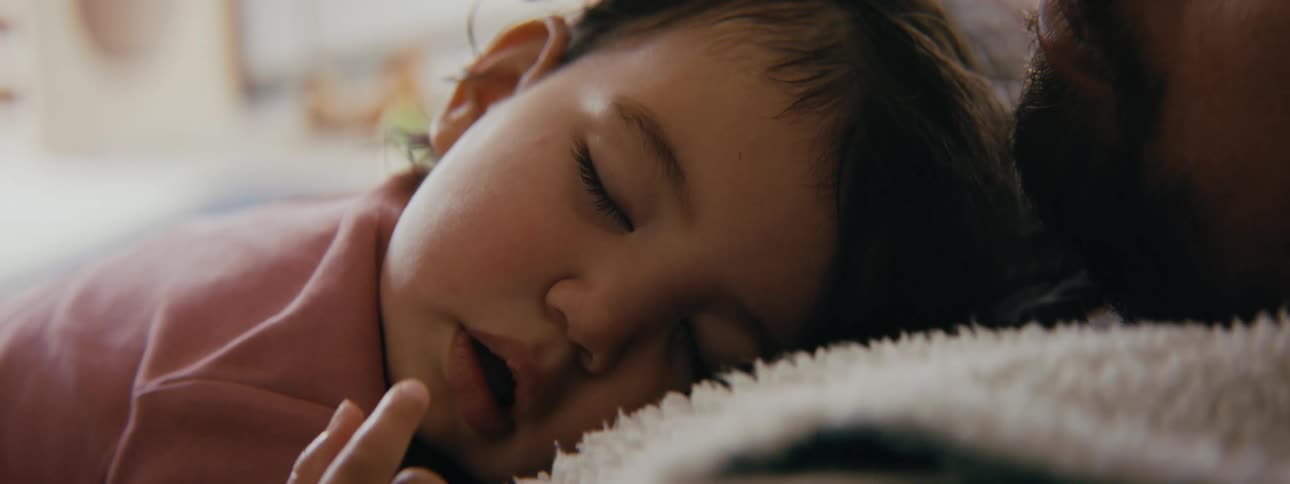 Daughter sleeps on fathers chest as he strokes head