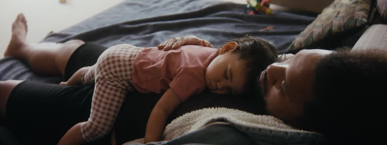 Daughter and father are taking a nap on the bed