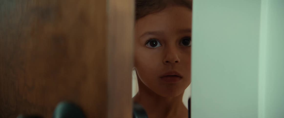Child stands near ajar door looking out