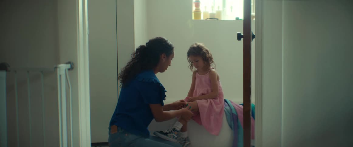 A woman bandages her daughters knee and hugs her